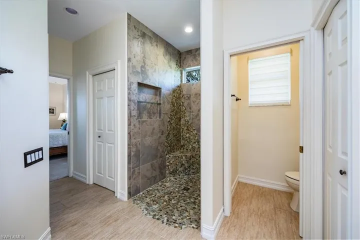 Master bathroom with custom tiled shower and windows that bring Naples sunshine into your room.