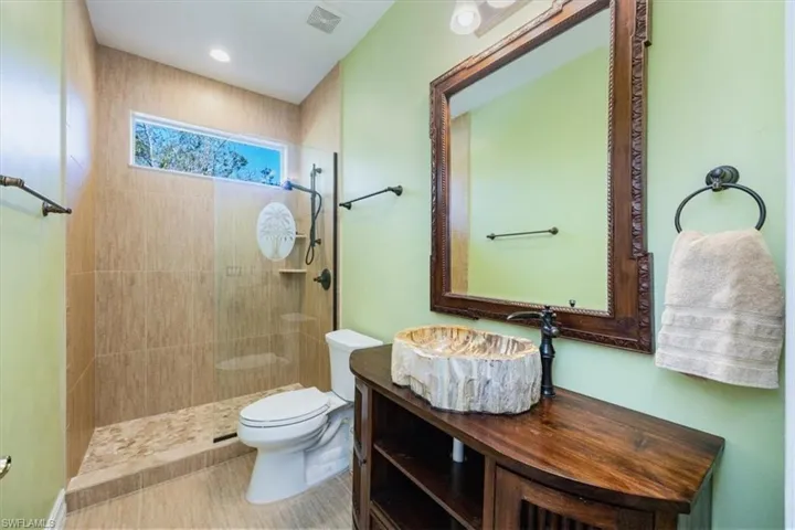 Guest bathroom with custom wooden sink and teak finishes bring elements we love in Florida into your living space.