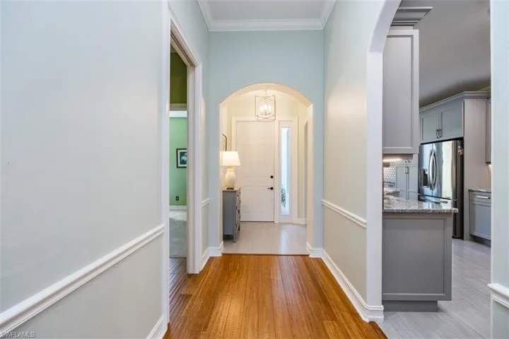Foyer with crown molding, lovely lighting throughout and light wood-flooring welcomes you into this coastal oasis.