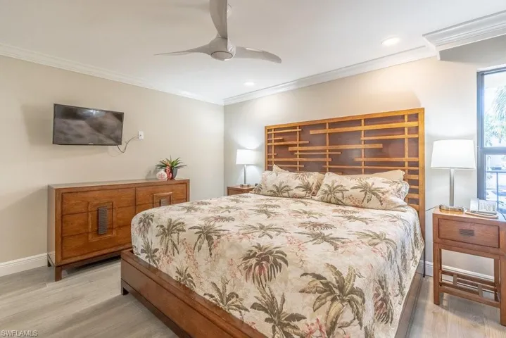Bedroom featuring light wood-type flooring, crown molding, and ceiling fan