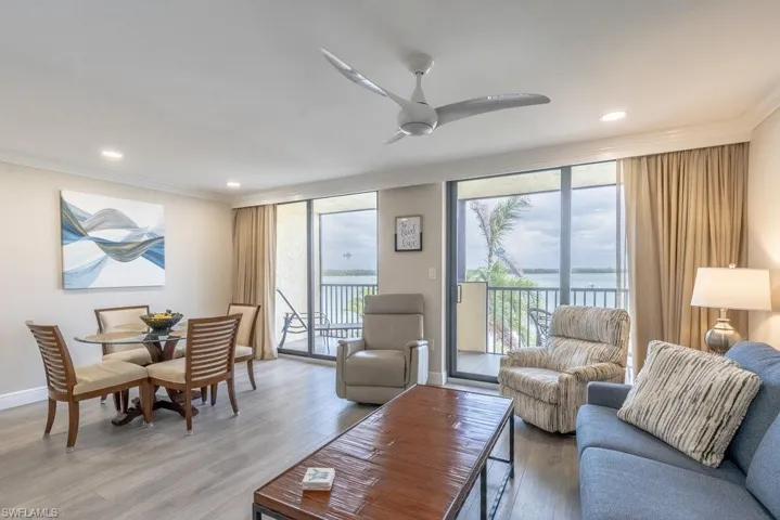 Living room with wood-type flooring, ornamental molding, and ceiling fan