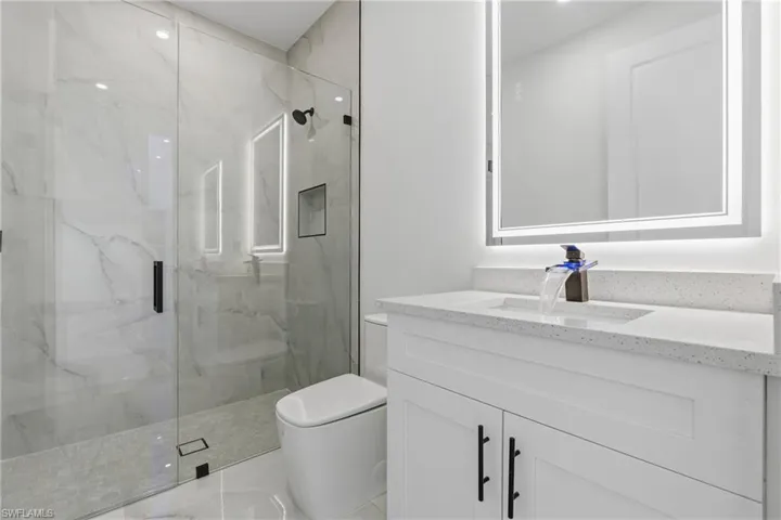 Full bath featuring vanity and a marble finish shower