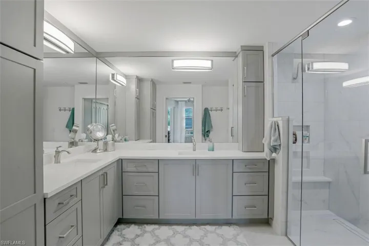 Full bathroom featuring a shower stall, double vanity, and recessed lighting