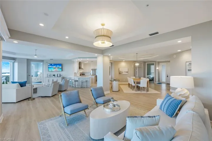 Living room with a tray ceiling, light wood-type flooring, and recessed lighting
