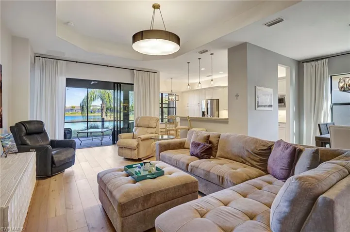 Living room featuring a water view, a raised ceiling, visible vents, and light wood-style floors
