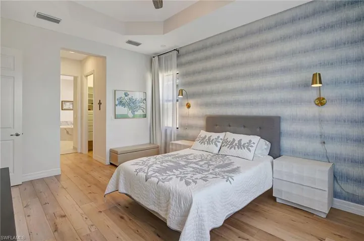 Bedroom featuring wood-type flooring, visible vents, a raised ceiling, and baseboards