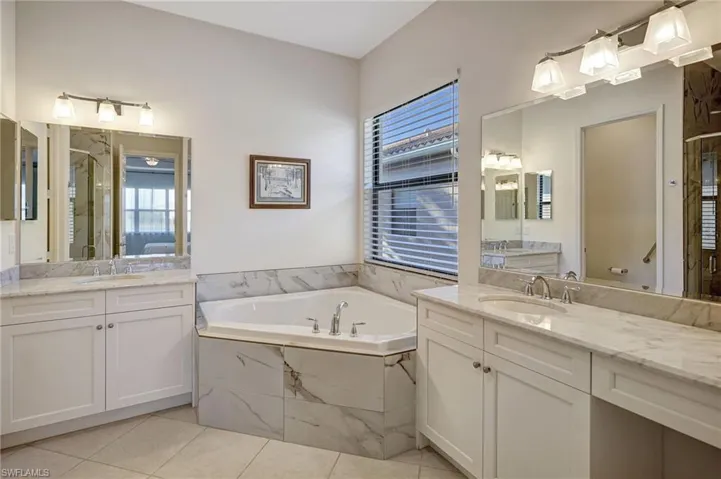 Bathroom with a stall shower, a garden tub, a sink, and tile patterned floors