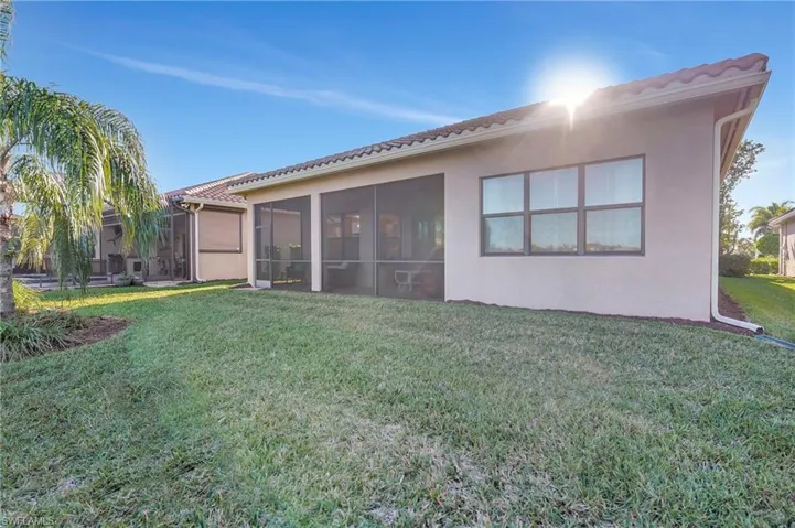 Back of house with a sunroom, a lawn, and stucco siding