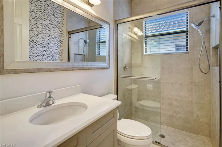Bathroom with vanity, a shower stall, and toilet