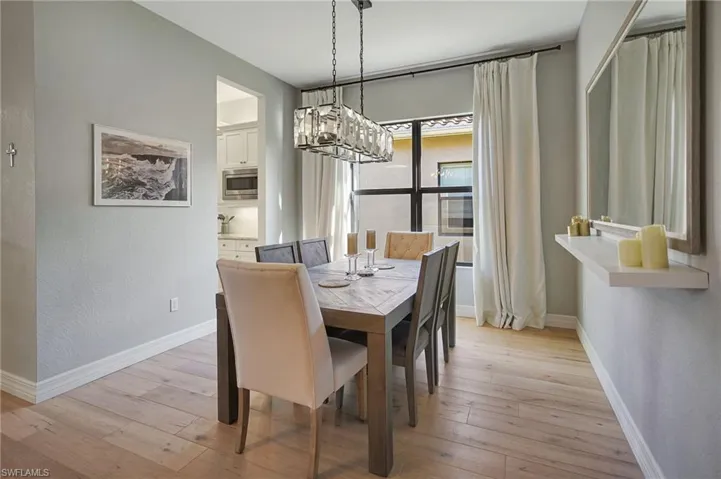 Dining room with a notable chandelier, light wood finished floors, and baseboards