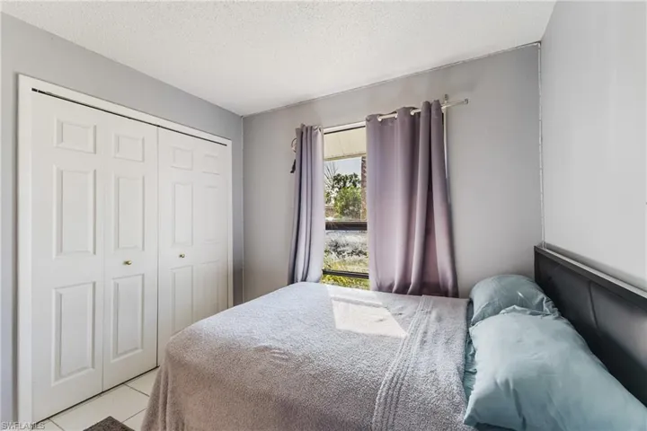 Tiled bedroom with a textured ceiling and a closet