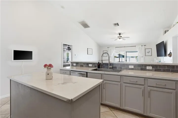 Kitchen with gray cabinetry, backsplash, lofted ceiling, ceiling fan, and dishwasher