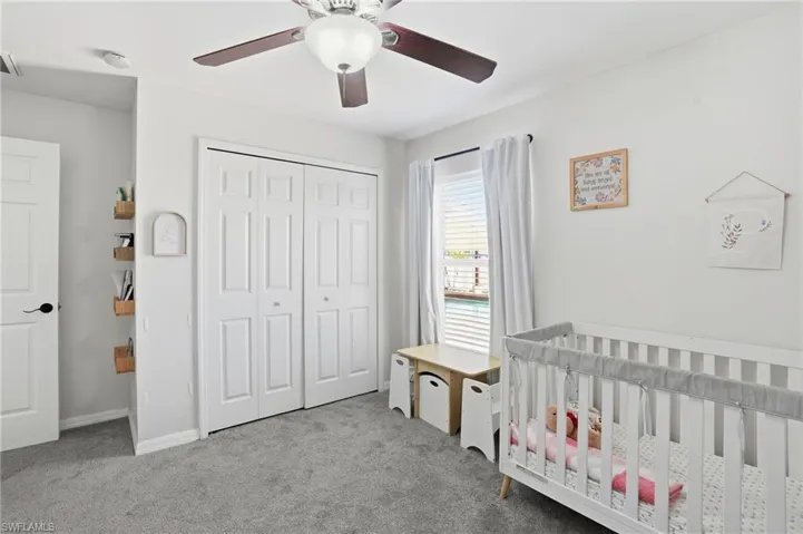 Bedroom with carpet, a closet, a ceiling fan, and a nursery area