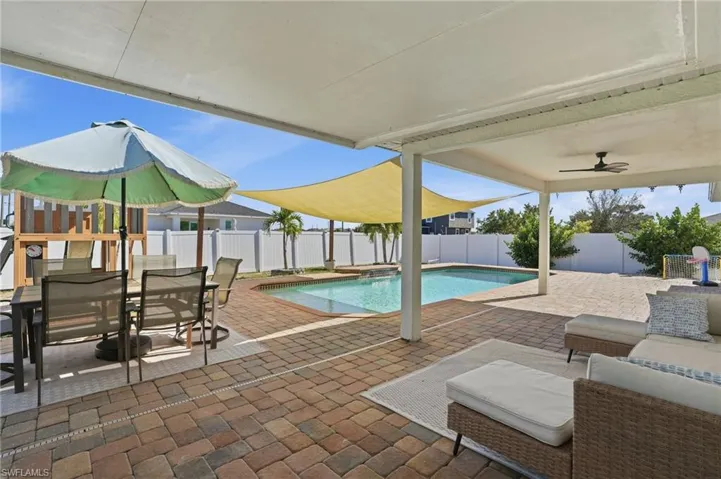 View of swimming pool with a patio, outdoor dining space, a fenced backyard, and a pool with connected hot tub