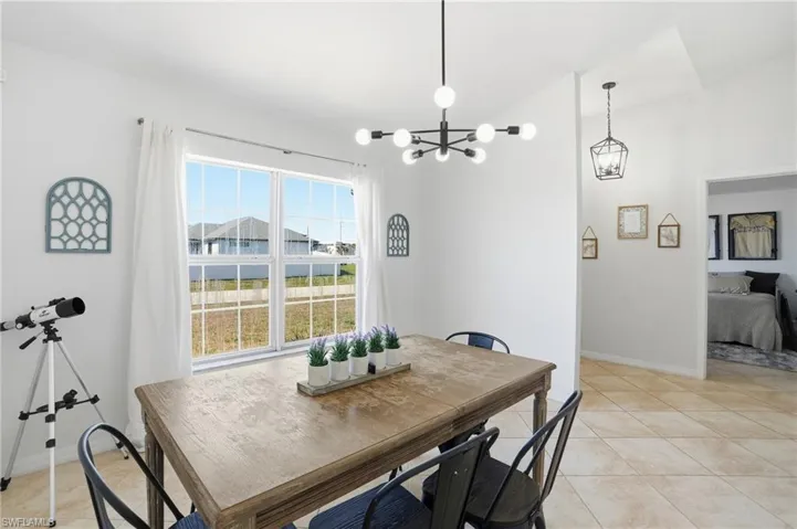 Dining space with light tile patterned floors, a chandelier, and lofted ceiling