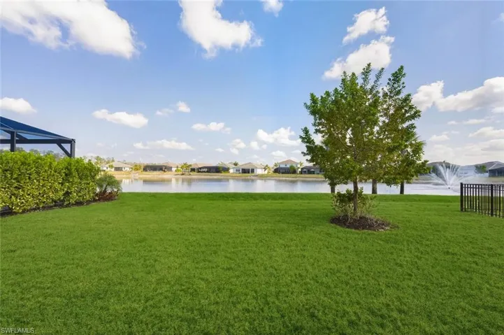 View of grassy yard featuring a water view, a residential view, and a lanai