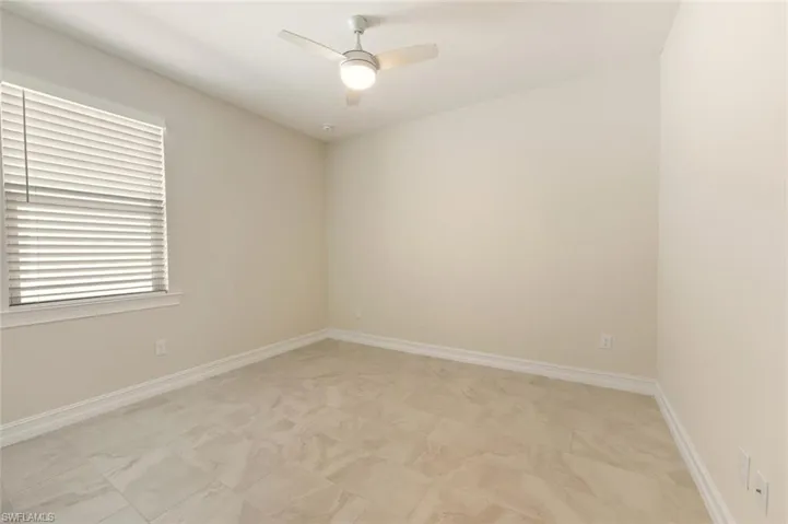 Empty room featuring a ceiling fan and baseboards