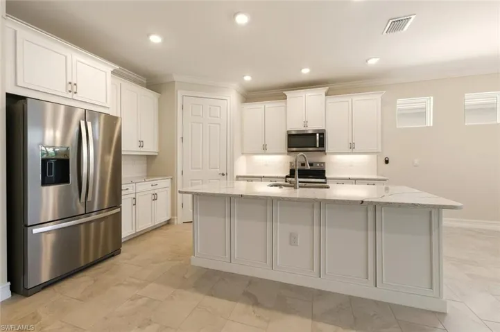 Kitchen featuring stainless steel appliances, white cabinetry, light stone countertops, decorative backsplash, and recessed lighting