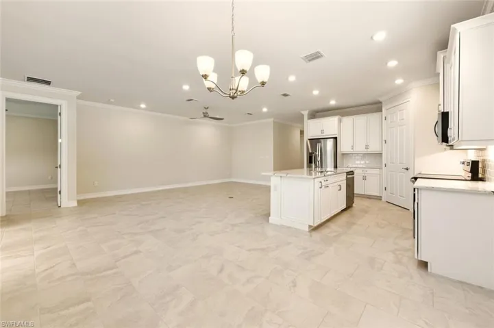 Kitchen with hanging lights, backsplash, open floor plan, white cabinets, and stainless steel appliances