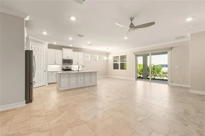 Kitchen with open floor plan, hanging lights, a ceiling fan, stainless steel appliances, and crown molding