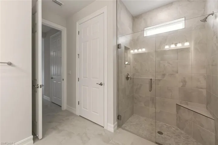 Full bathroom featuring a shower stall and baseboards