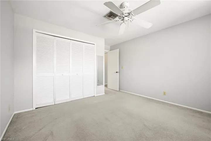 Spacious room featuring light gray wall paint, white trim, and gray carpet flooring