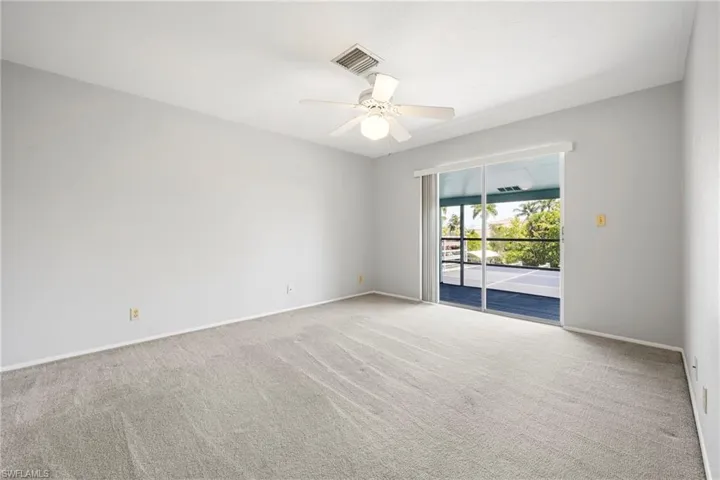 Light gray wall paint with baseboard trim, ceiling fan, and sliding glass doors opening to a screened lanai