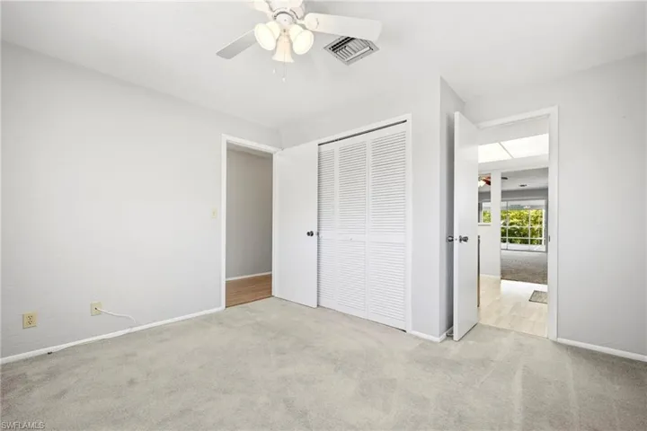 Room featuring light gray carpeting, neutral wall finishes, and a ceiling fan with integrated lighting