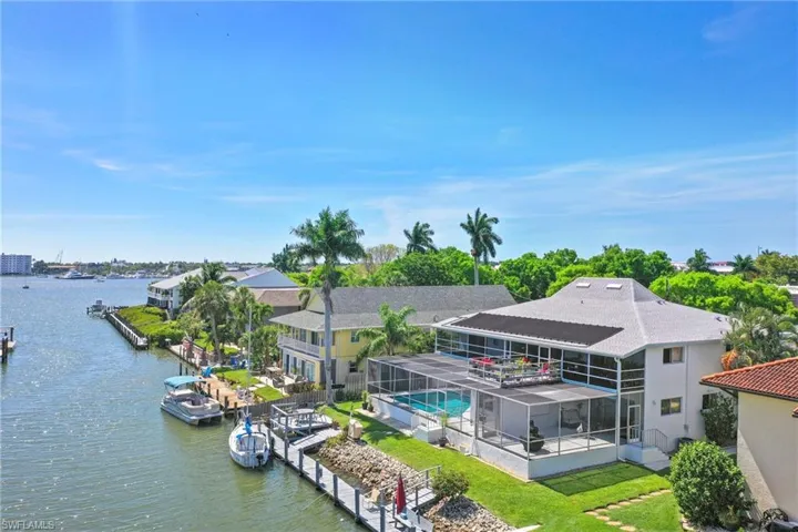 Waterfront property featuring a screened-in lanai with a pool, multiple boat docks, and direct access to open water