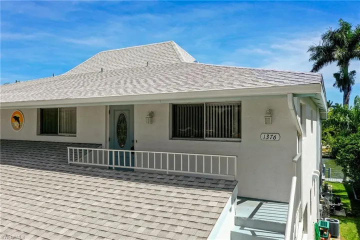 Multi-level residence featuring a light-colored shingle roof and white stucco exterior