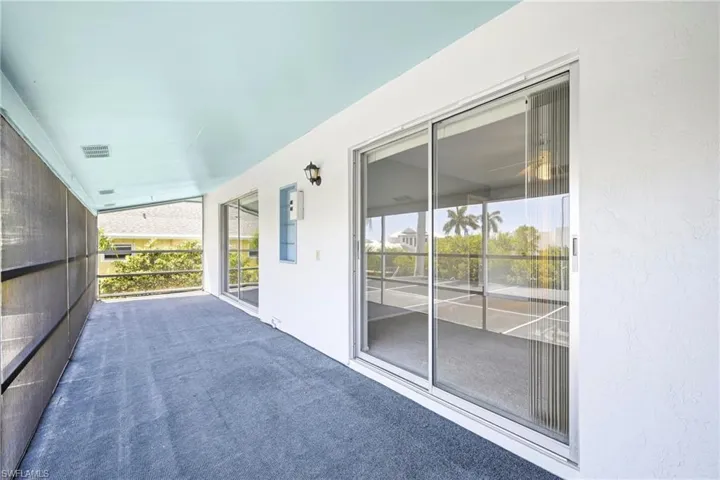 Screened-in outdoor living space with a textured floor and light blue ceiling