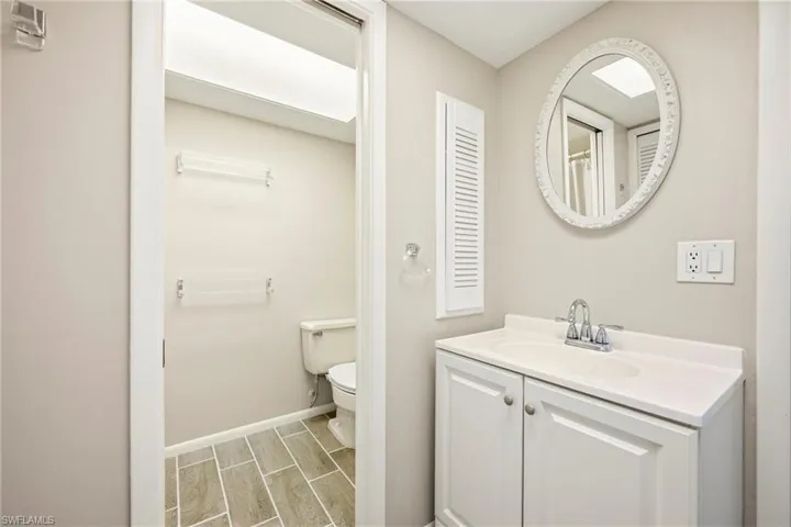 Bathroom featuring a white vanity with integrated sink, chrome faucet, and decorative oval mirror