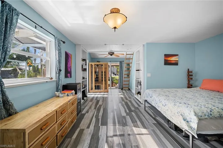 Spacious room featuring wood-finish flooring, a contemporary ceiling fan, and built-in shelving