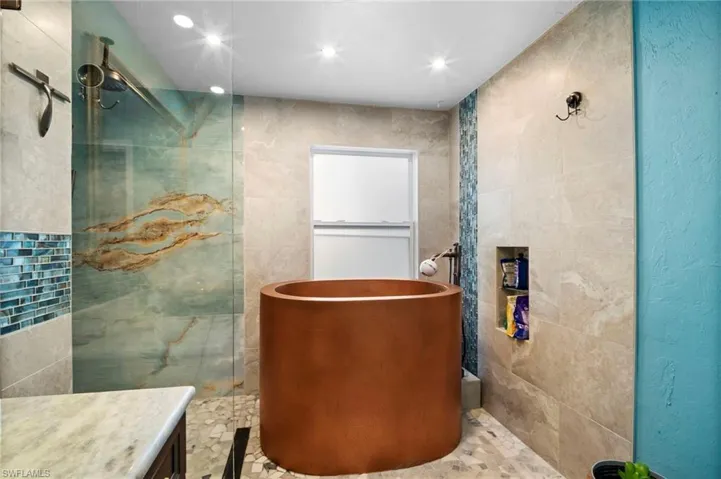 Contemporary bathroom featuring a circular soaking tub, glass-enclosed shower with a rainfall showerhead, and a mosaic tile accent wall