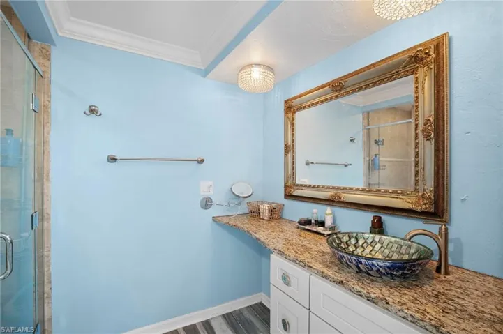 Bathroom featuring a glass-enclosed shower, a vanity with a granite-look countertop, a decorative vessel sink, and a framed mirror