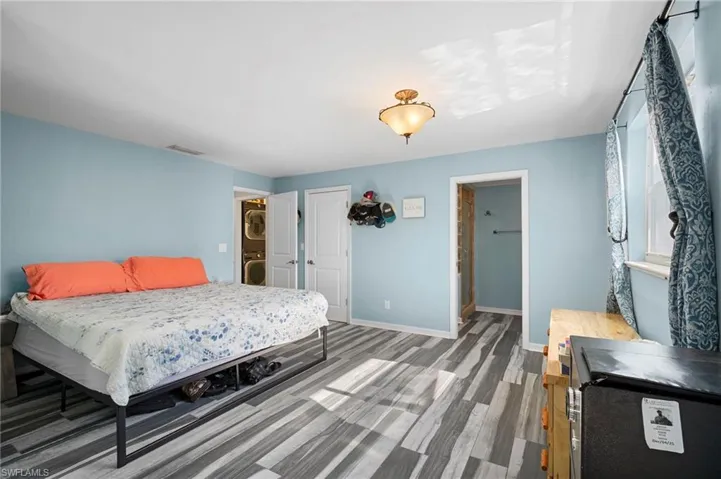Spacious room featuring wood-finish flooring, light blue walls, and a ceiling-mounted fixture