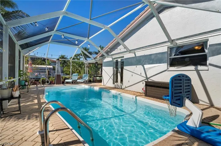 Screened enclosure featuring a swimming pool, paved pool deck, and direct access to the interior via glass doors