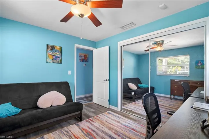 Interior room featuring a ceiling fan with light fixture, wood-finish flooring, and a mirrored closet