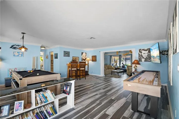 Spacious entertainment area featuring wood-finish flooring, light blue walls, and white crown molding