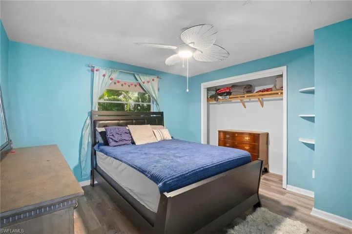 Bedroom featuring wood-finish flooring, a ceiling fan, and a window providing natural light