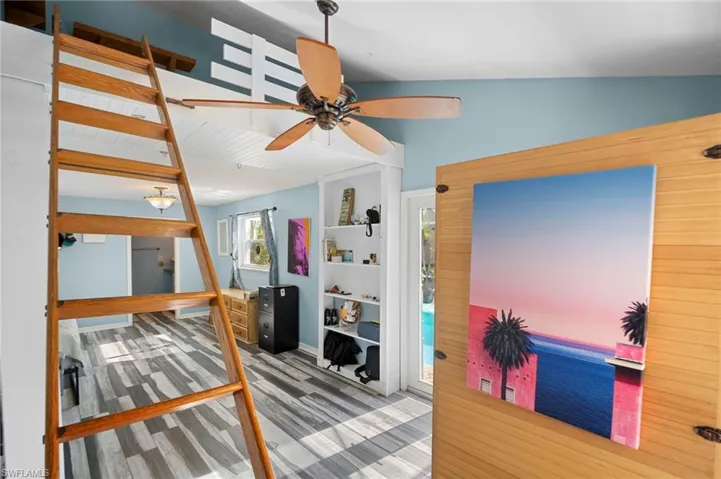 Interior space featuring a built-in wooden ladder leading to an upper loft area with slatted white railing