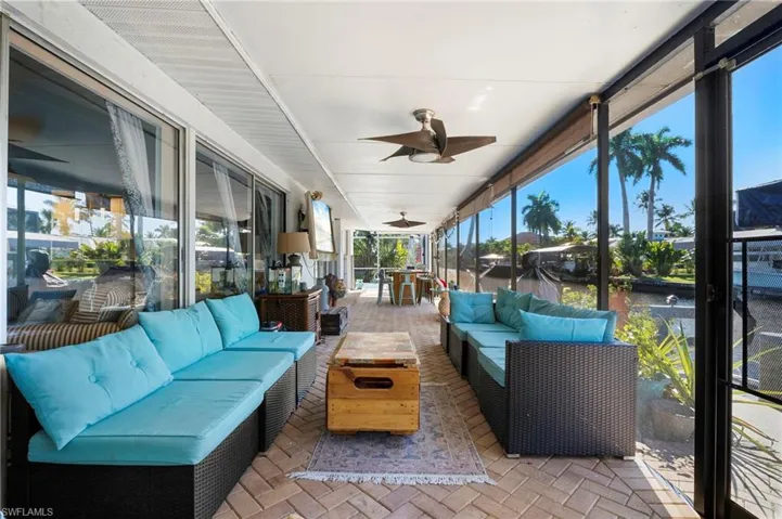 Expansive screened lanai featuring brick paver flooring and ceiling fans