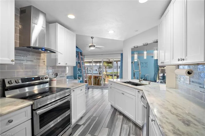 Contemporary kitchen featuring white cabinetry, light countertops, wood-finish flooring, a stainless steel range, and an island with a built-in sink