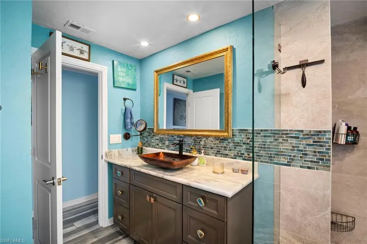Vanity with a vessel sink, stone countertop, and custom base cabinetry
