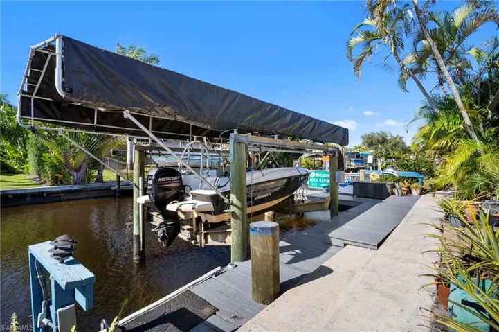 Waterfront dockage featuring a boat lift with canopy, composite decking, and canal access