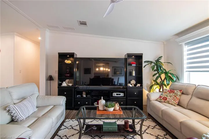 Living area featuring crown molding, wood finished floors, and ceiling fan