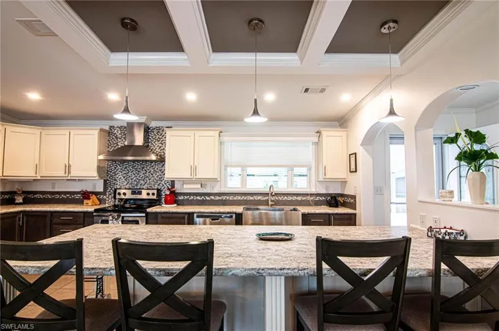 Kitchen with a kitchen breakfast bar, tasteful backsplash, arched walkways, stainless steel appliances, and ornamental molding