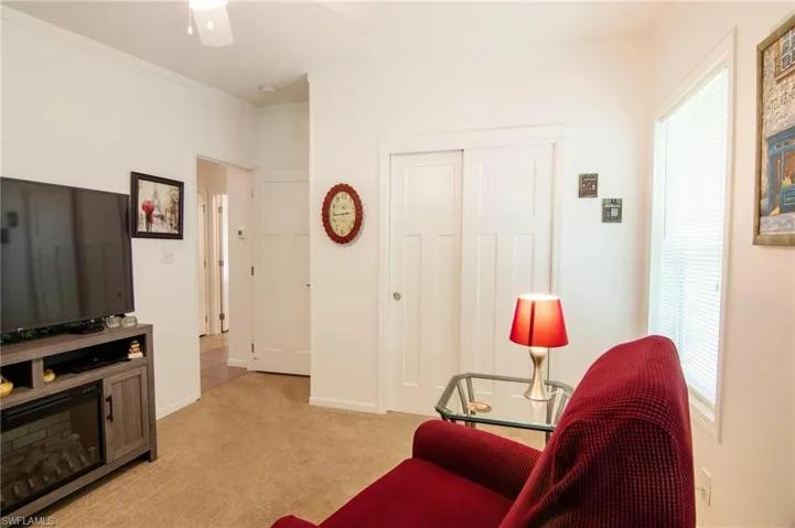 Living area featuring light colored carpet and ceiling fan