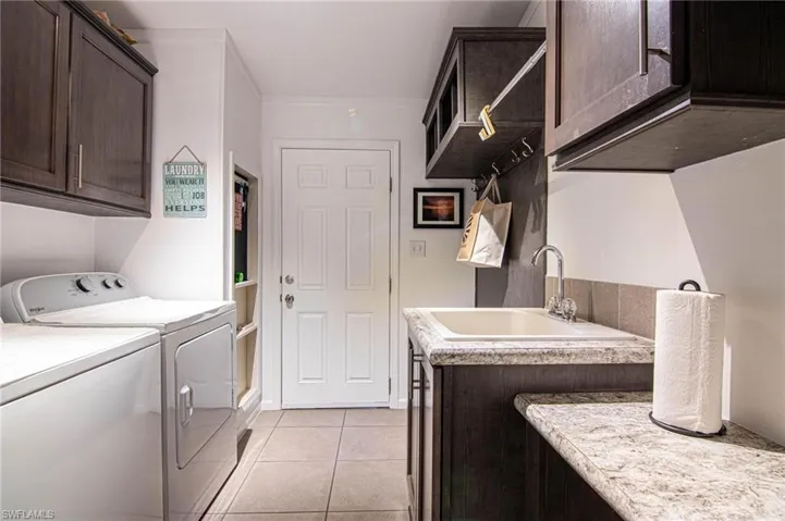 Washroom featuring cabinet space, light tile patterned floors, and independent washer and dryer