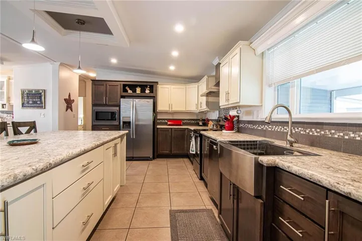Kitchen featuring backsplash, stainless steel appliances, lofted ceiling, white cabinets, and dark brown cabinets